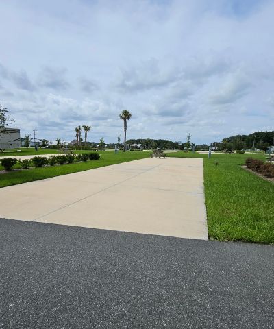 Empty paved path with grass on both sides under cloudy sky.