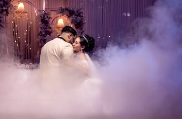 A couple shares an intimate moment surrounded by mist and soft lighting.