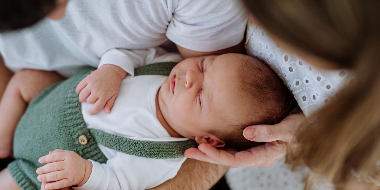 Newborn baby comfortably sleeping in parent's arms.