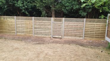 Wooden fence with a small gate in a backyard.