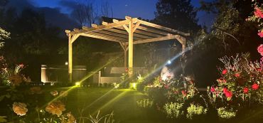 Garden pergola illuminated at night with flowers.