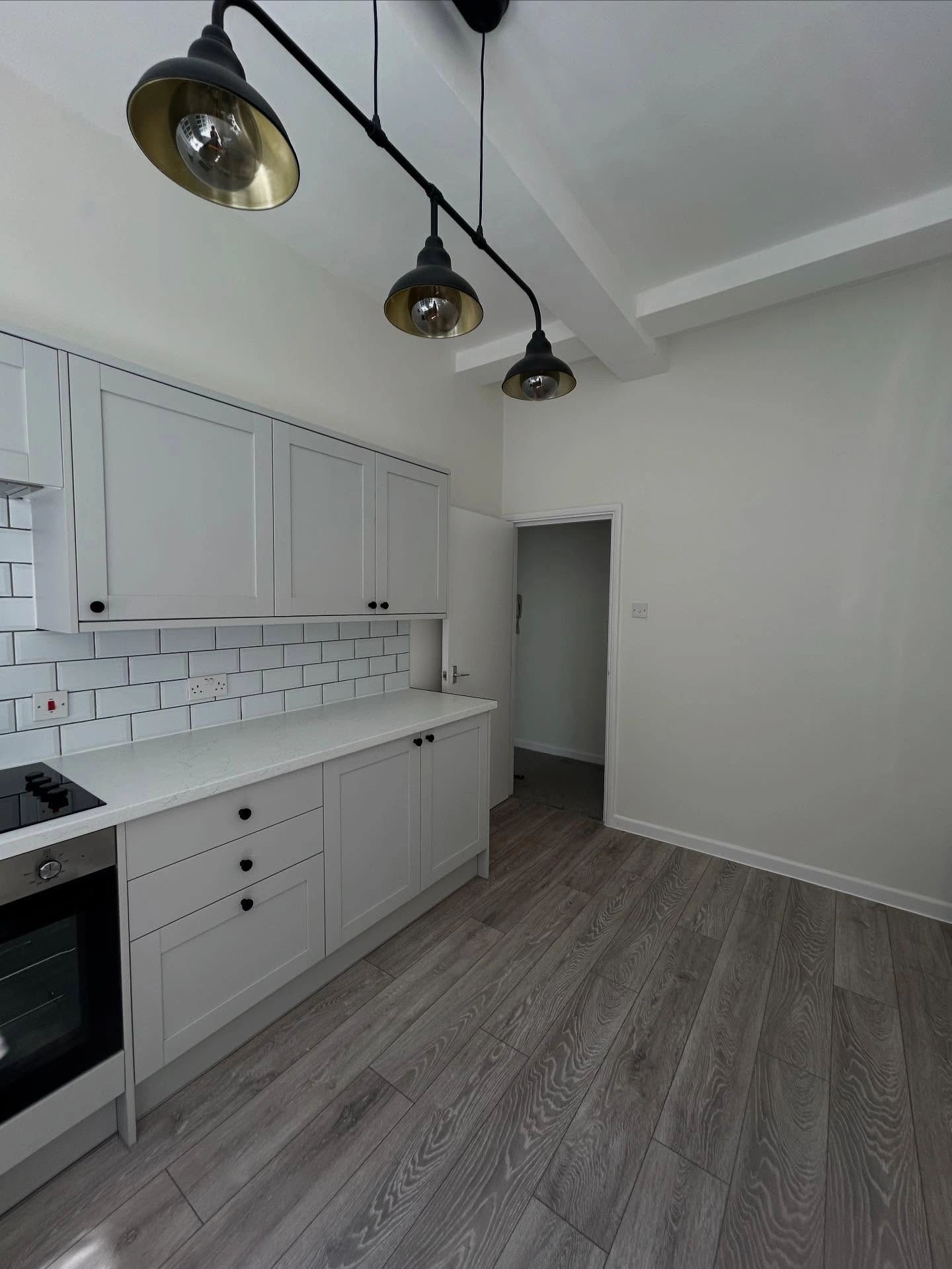 Modern kitchen with white cabinets, subway tile backsplash, and wood-look flooring.