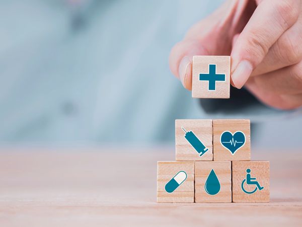 Businessman chooses an emoticon icons healthcare medical symbol on wooden block,