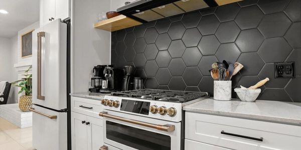 Newly remodeled kitchen with black tile, white shaker cabinets and a new white, high-end appliances t