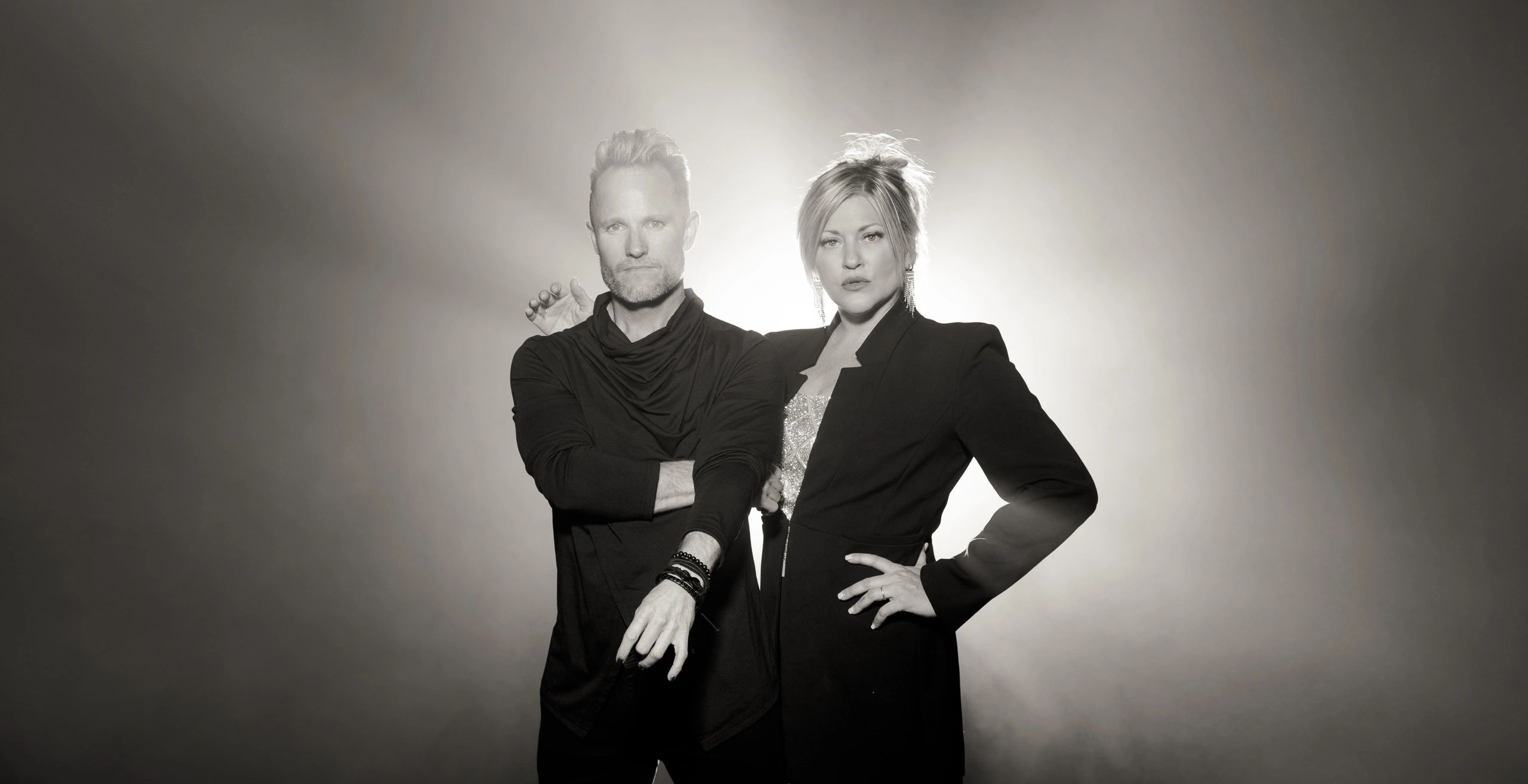 A stylish man and woman posing confidently in black and white.