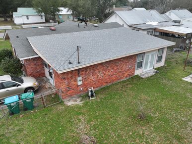 A brick house with a gray roof and a green lawn.