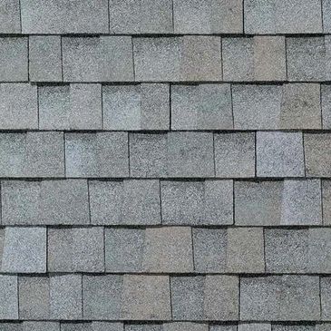 Close-up of grey asphalt roof shingles arranged in overlapping rows.