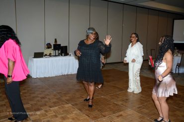 Four women dancing and enjoying themselves at an indoor event.