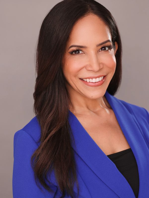 Confident woman smiling, wearing a vibrant blue blazer against a neutral background.