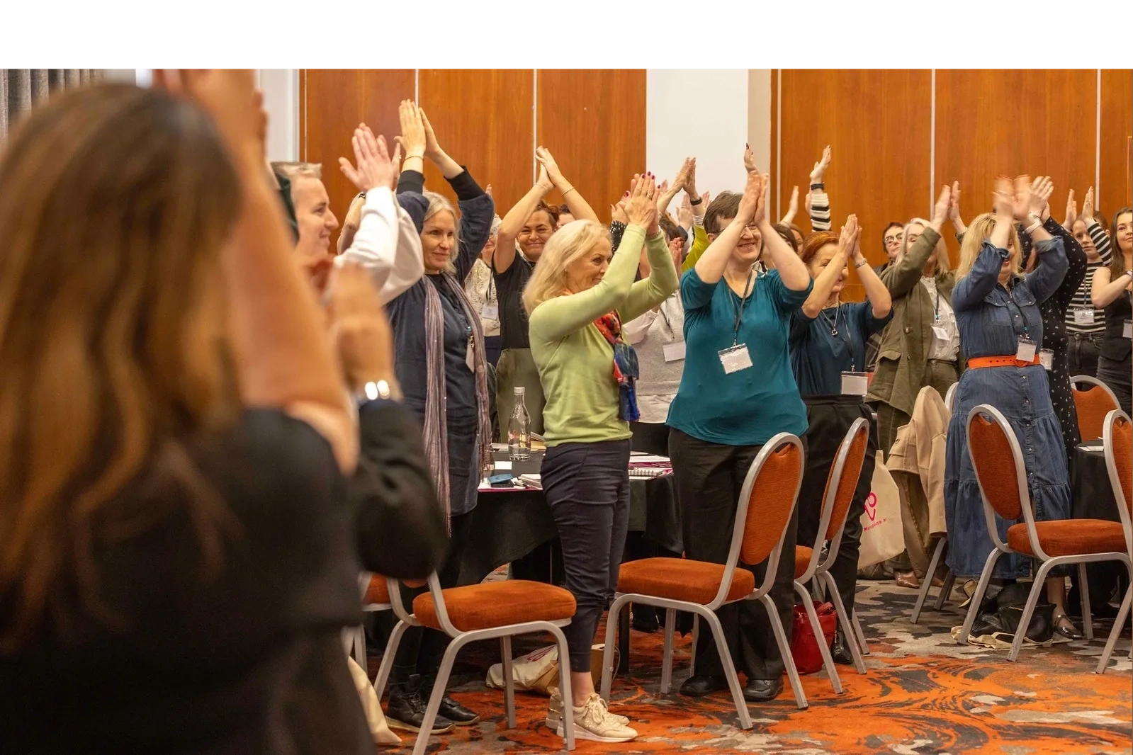 Group of people clapping and standing in a conference room.