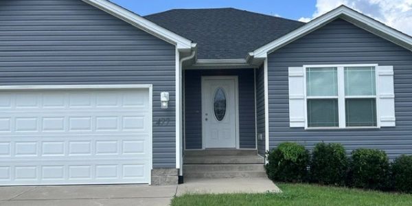 Blue house with white garage door and front door.