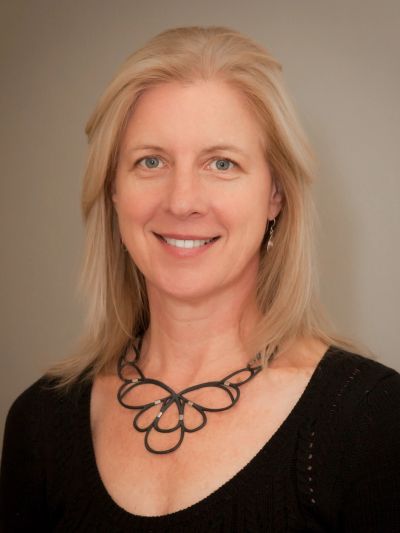 Smiling woman with blonde hair and a black necklace.