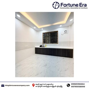 Modern kitchen with sleek black cabinets and white marble flooring under recessed ceiling lights.