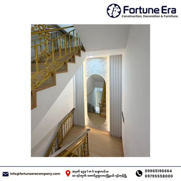 Elegant staircase with golden railing and modern mirror in a bright hallway.