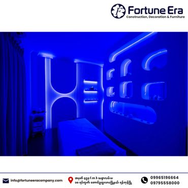 A modern, blue-lit spa or therapy room with sleek wall niches and a massage table.