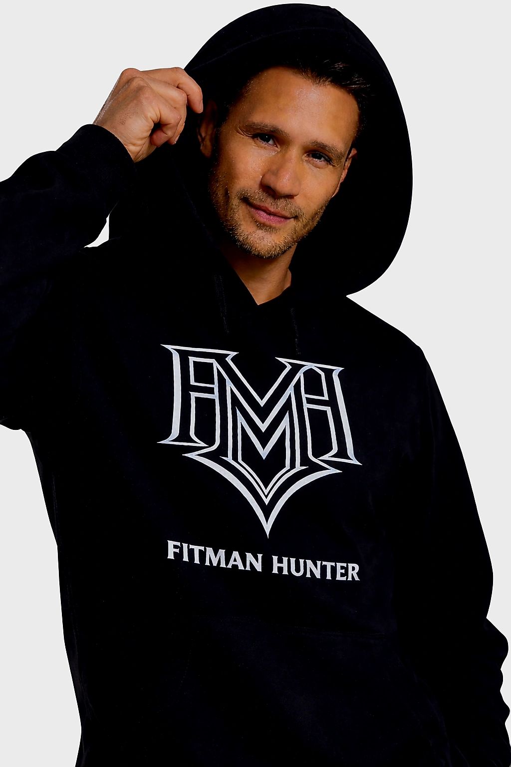 Man wearing a black Fitman Hunter hoodie with a hood up.