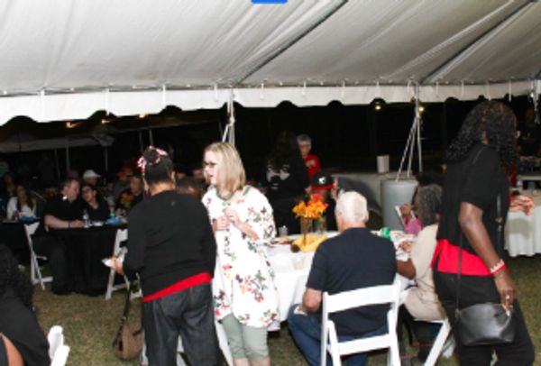 People socializing under a large white event tent at night.