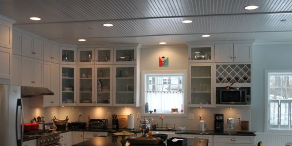 Country kitchen featuring white shaker cabinets, stainless steel appliances,  farm sink, bead board 