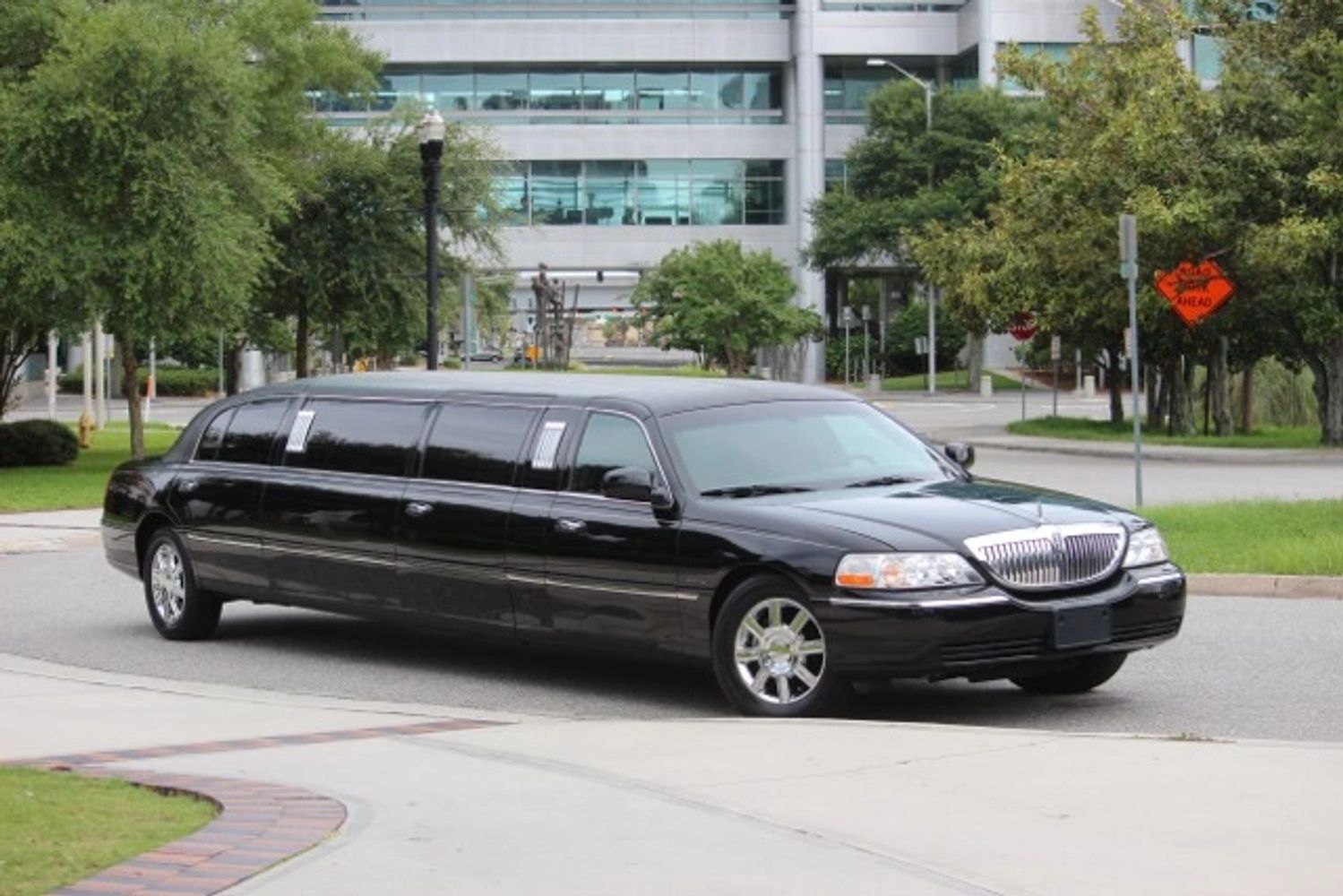 Black stretch limousine parked near a modern office building.