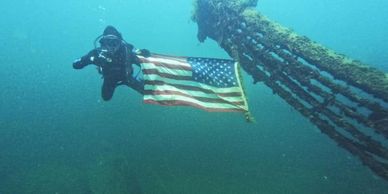 scuba diver holds American flag underwater at gilboa quarry