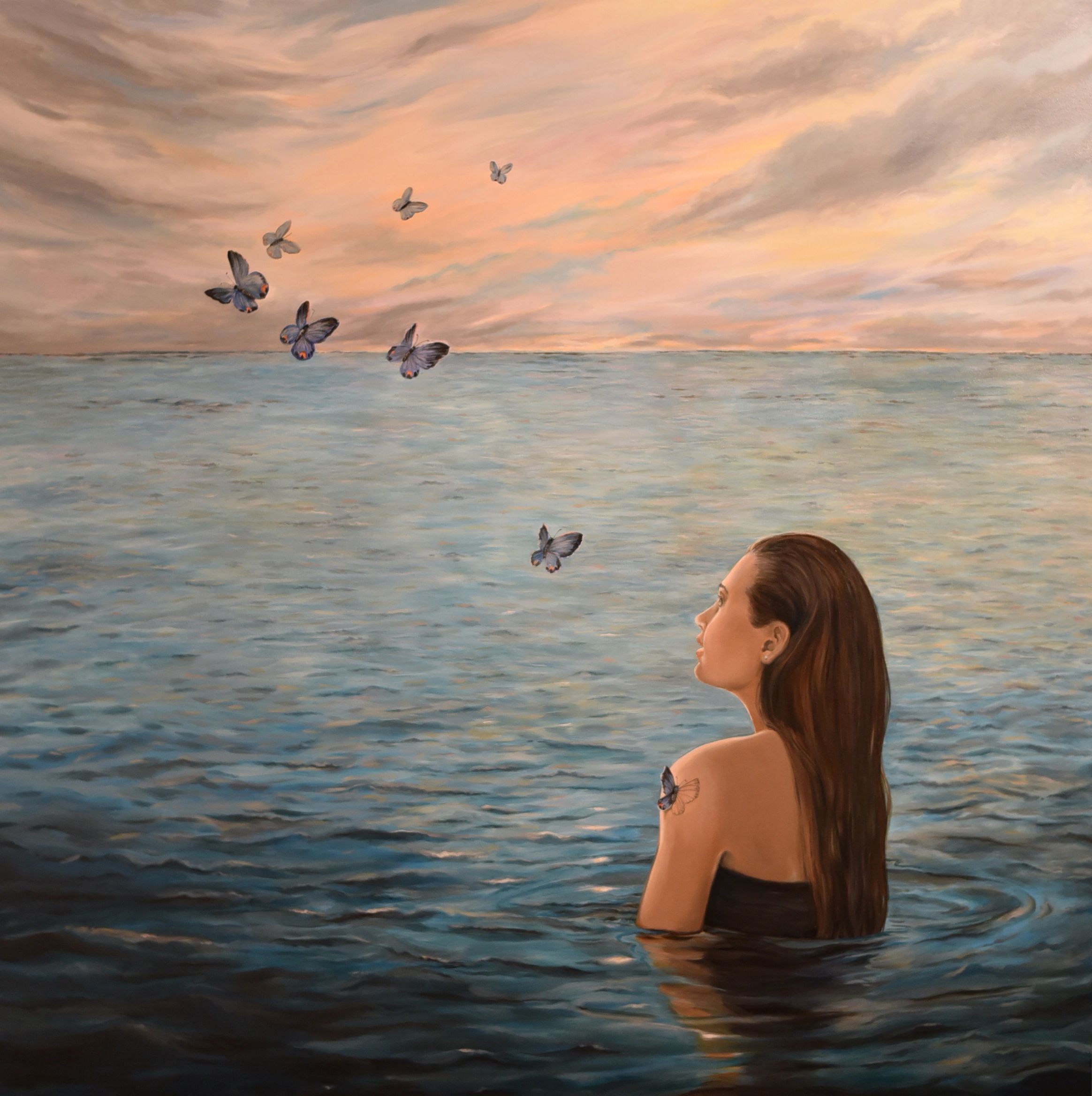 A woman in water watches butterflies flying at sunset.