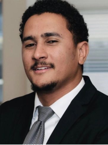 A young man in a suit and tie smiling confidently.