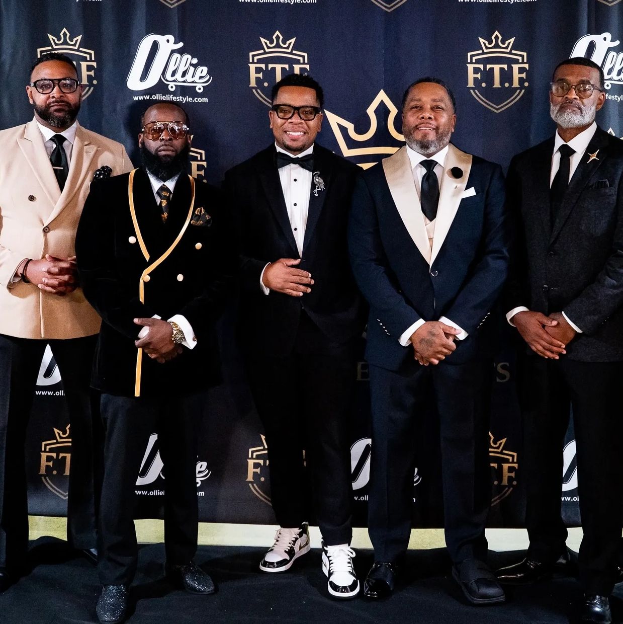 Group of five men in suits posing for a photo.