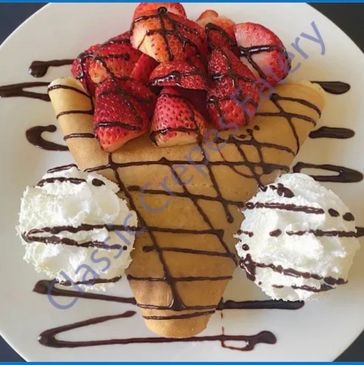 Crepe with strawberries, chocolate drizzle, and whipped cream.