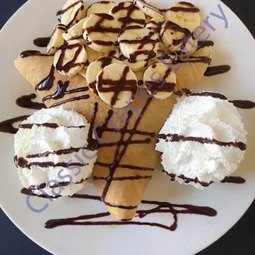 Dessert with whipped cream, banana slices, and chocolate drizzle.