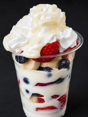 Fruit parfait with strawberries, blueberries, bananas, and whipped cream.