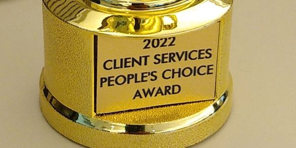 Golden trophy for Client Services People's Choice Award 2022 on a desk.