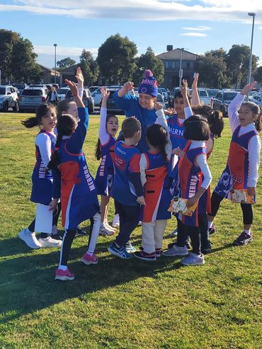 Mernda Junior Team cheering with hands in the air. 