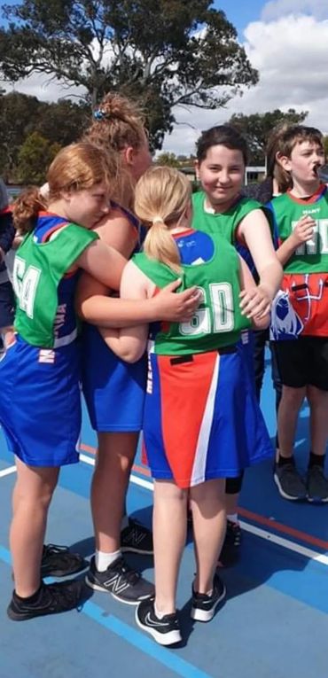 Mernda Players cuddling in a group. 