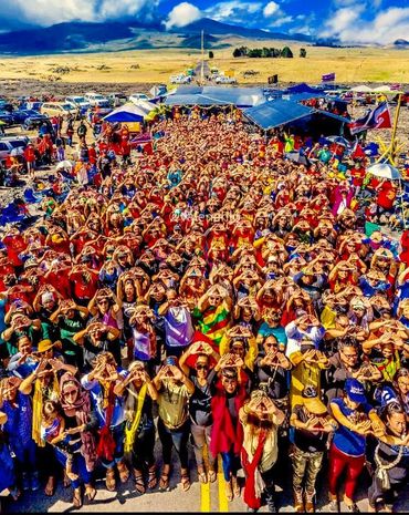 The people form a mountain-shape with their hands, representing Protect Mauna Kea   