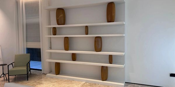 Minimalist white shelving unit with wooden decorative items in a modern room.