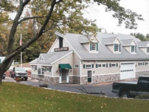 A quaint building with dormer windows and a green awning.
