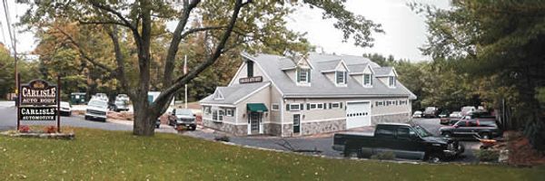 A large, barn-style building with parked trucks around it.