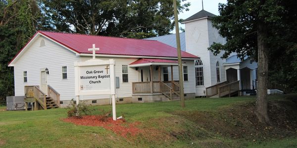 Oak Grove Missionary Baptist Church building with a red roof and white exterior.