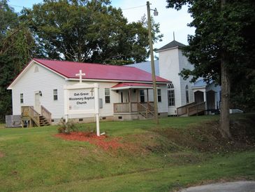 Oak Grove Missionary Baptist Church building with a red roof and white exterior.