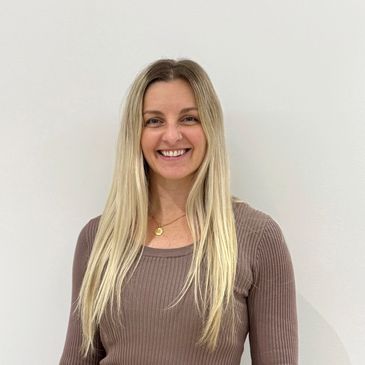 Smiling woman with long blonde hair in a brown top.