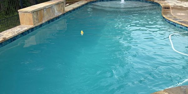 A clean swimming pool with a small yellow duck floating in the water.