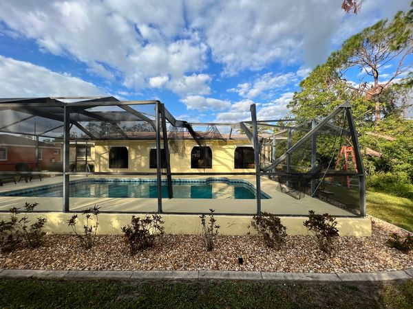 Pool Screen Enclosure damaged with a tree branches during a hurricane strong wind gusts, bending 3 m