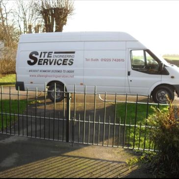 White van with Site Engineering Services logo parked behind a wrought iron gate.
