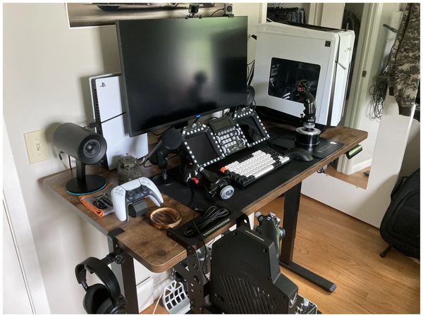 Gaming and simulation setup with monitor, joystick, PlayStation console, and racing chair.
