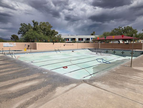 Empty swimming pool with cloudy sky above.