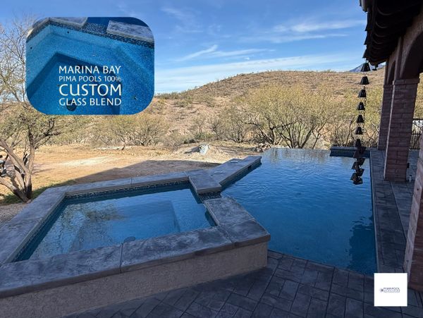 Infinity pool and spa with desert hill view under clear blue sky.