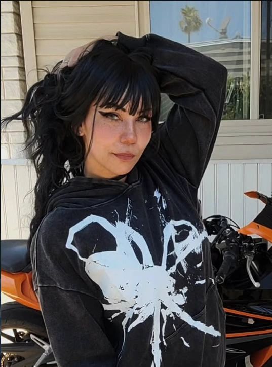 Young woman with black hair and a spider hoodie.