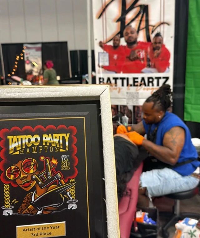 Tattoo artist working with an award for Tattoo Party Hampton in the foreground.