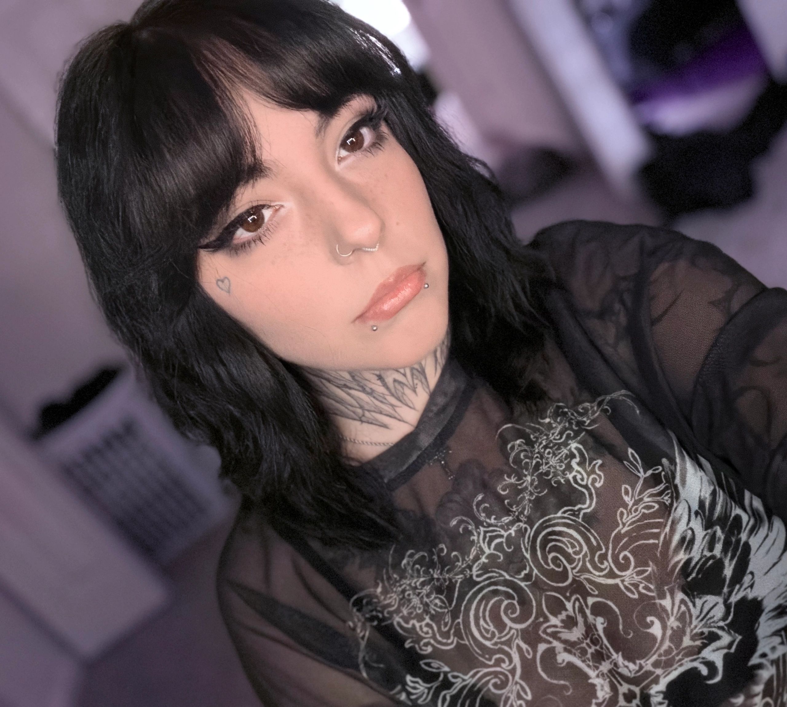 Close-up of a person with black hair and facial piercings.