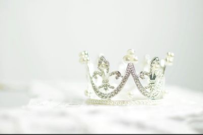 A delicate silver crown adorned with shiny gems on a white surface.